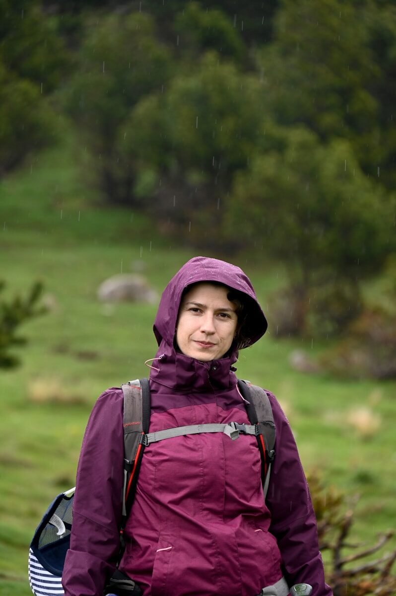 A woman in a purple jacket is standing in the rain